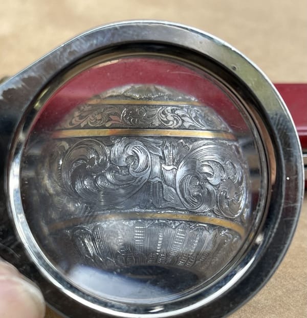 Engraved rifle bolt knob seen through a magnifying glass
