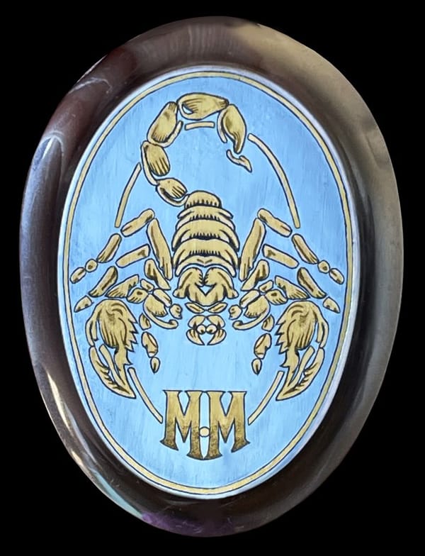 Griffkappe mit goldenem Skorpion und den Initialen MM auf blauem Grund